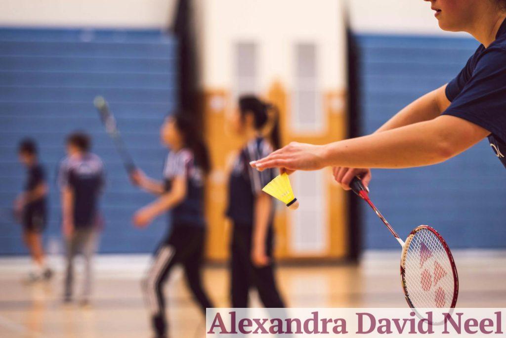 A group of young people enjoying a fun game of badminton indoors.