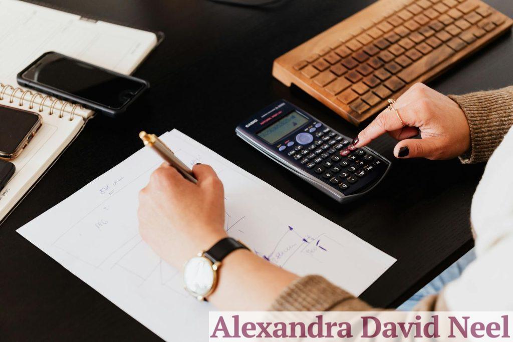 Close-up of hands working with a calculator and notebook on a desk, analyzing documents.