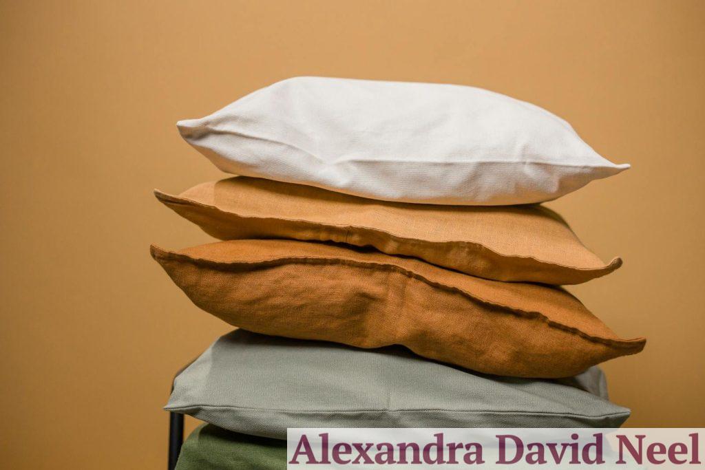 Stack of different colorful pillows folded and placed in stack on chair isolated on dark beige background